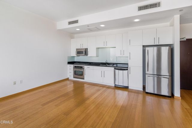 a kitchen with stainless steel appliances a refrigerator and wooden floor