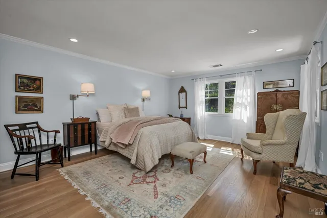 a spacious bedroom with a bed a couch and a dresser with wooden floor