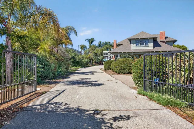 a view of a brick house with a small yard and a large parking space