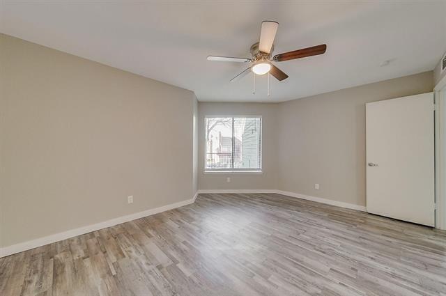 9815 Walnut Street, Unit 212 Dallas, TX 75243 - Photo 7 of 10 Spacious room featuring wood-finish flooring, neutral paint, a ceiling fan with light fixture, and a window with natural light