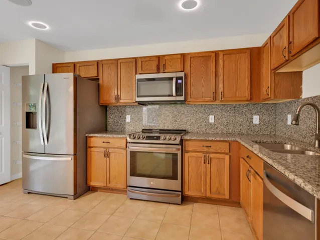 a kitchen with stainless steel appliances granite countertop a refrigerator a stove a sink and a microwave