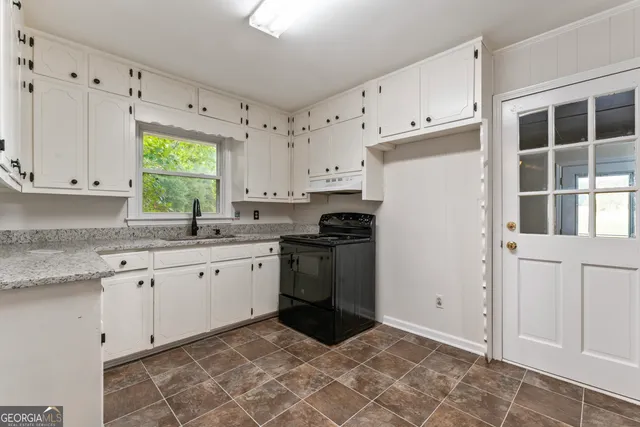 a kitchen with granite countertop a sink stove and cabinets