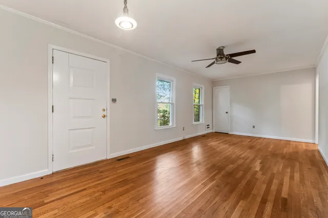 a view of an empty room with window and wooden floor