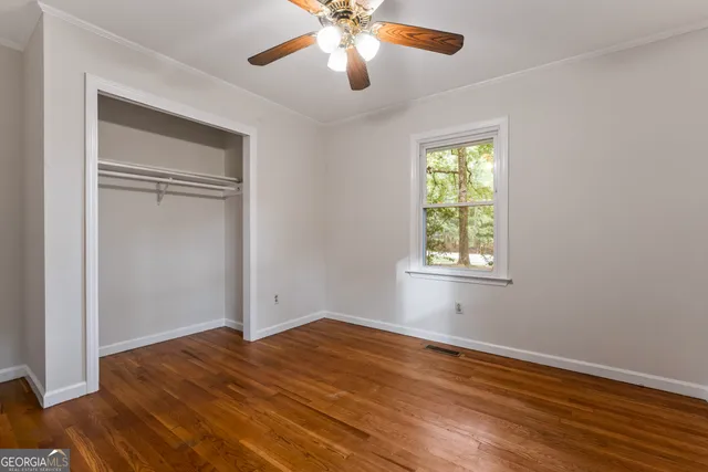 an empty room with wooden floor cabinet and windows