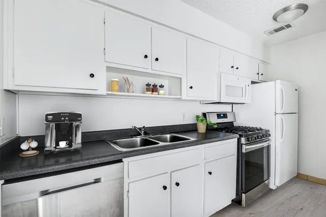 a kitchen with white cabinets and refrigerator