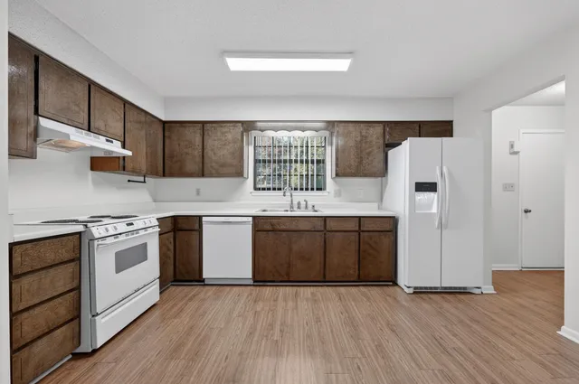 a kitchen with granite countertop wooden floors and white stainless steel appliances
