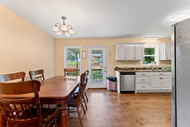 a open dining room with stainless steel appliances kitchen island granite countertop furniture and wooden floor