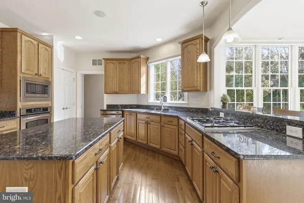 a large kitchen with granite countertop a large window and white cabinets