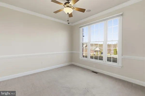 an empty room with chandelier fan and windows