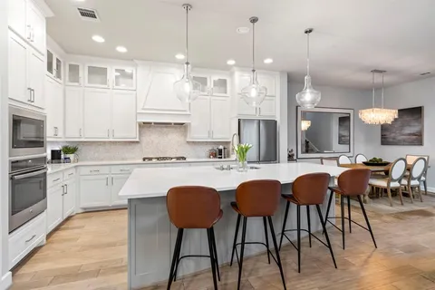 a kitchen with stainless steel appliances granite countertop a stove a sink a kitchen island with chairs and wooden floor