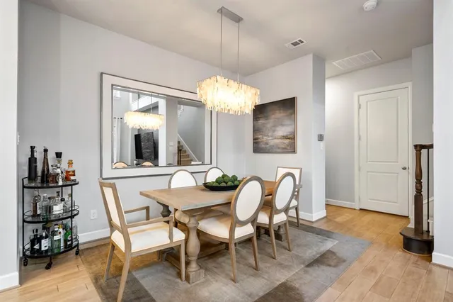 a dining room with wooden floor a chandelier a glass table and chairs