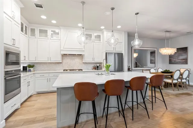 a kitchen with stainless steel appliances granite countertop a stove a sink a kitchen island with chairs and wooden floor