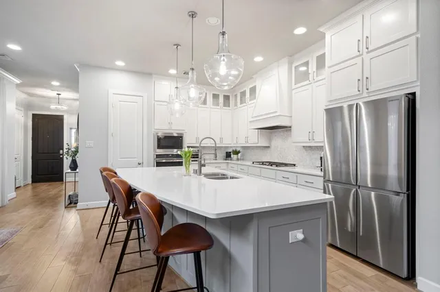 a kitchen with stainless steel appliances a dining table chairs stove refrigerator and cabinets