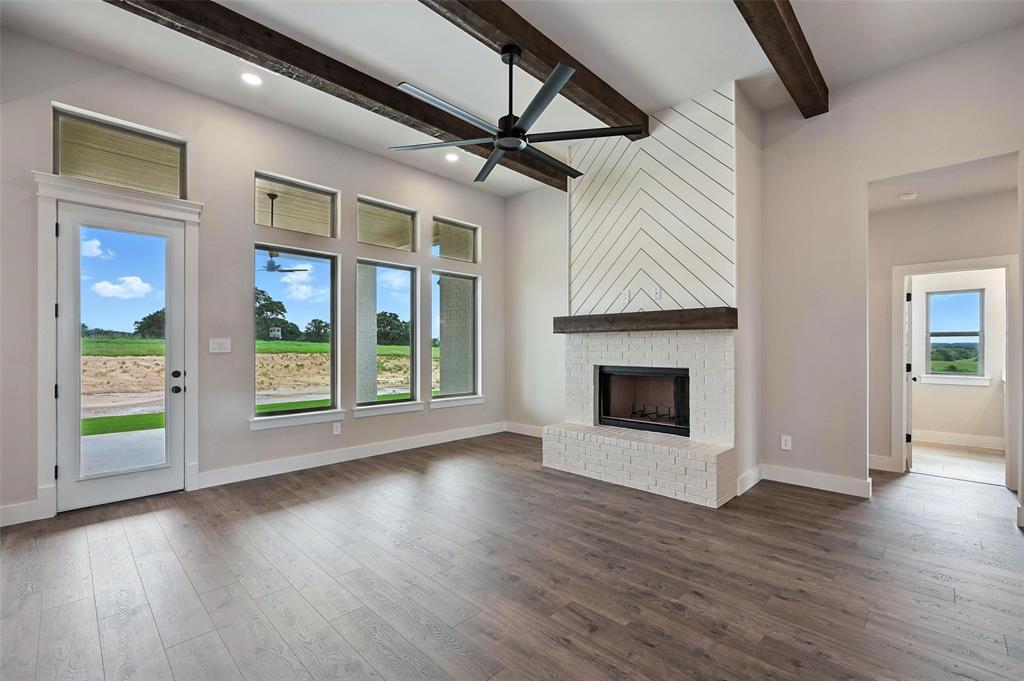 224 Kilkenny Road Poolville, TX 76487 - Photo 4 of 32 a view of an empty room with wooden floor fireplace and a window