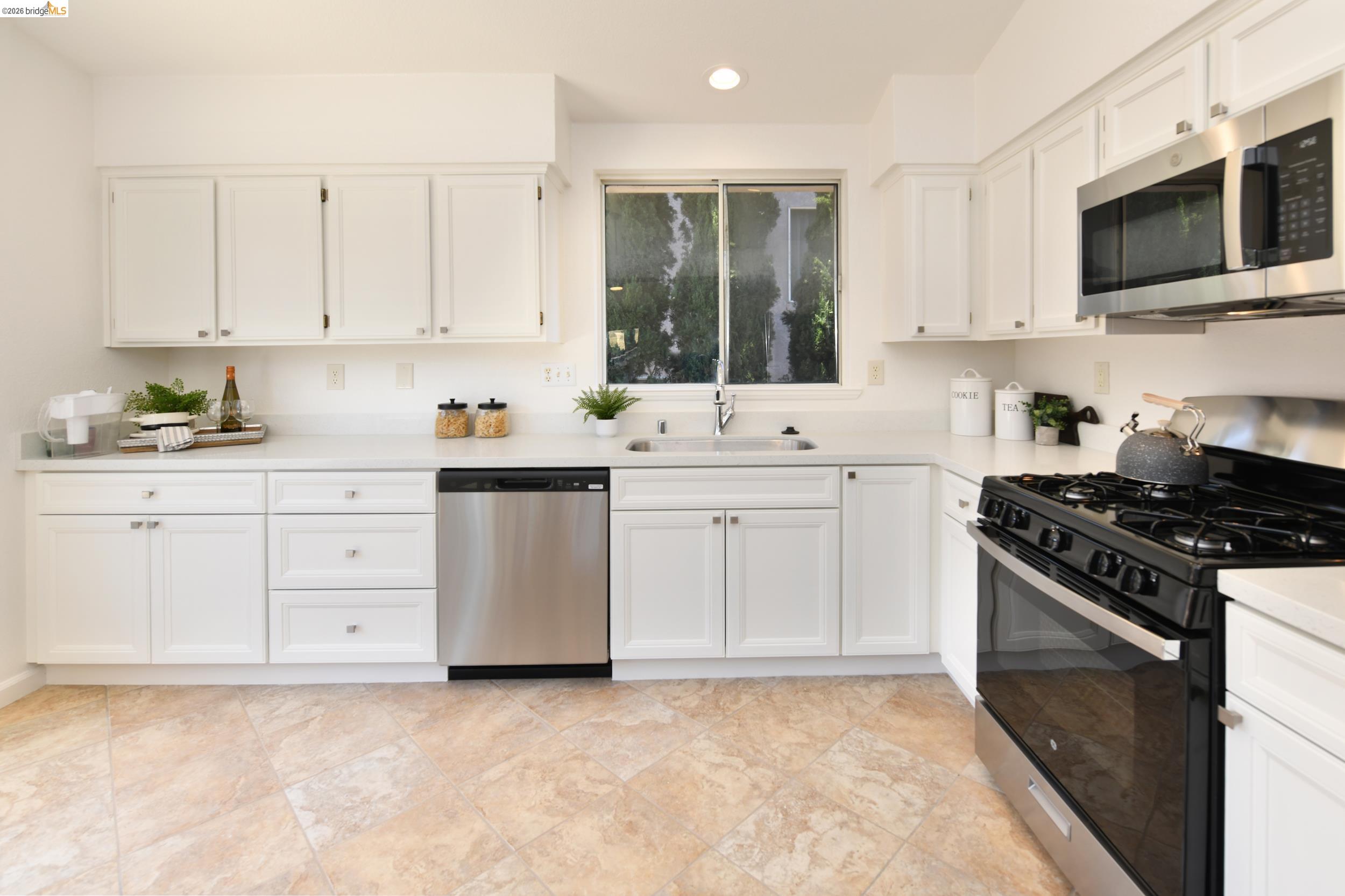 512 Burdick Drive Bay Point, CA 94565 - Photo 14 of 50 Kitchen featuring white cabinetry, light-toned countertops, tile flooring, stainless steel dishwasher, and a gas range with an overhead microwave