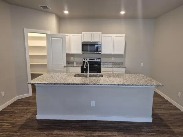 a view with kitchen island granite countertop a stove and a sink