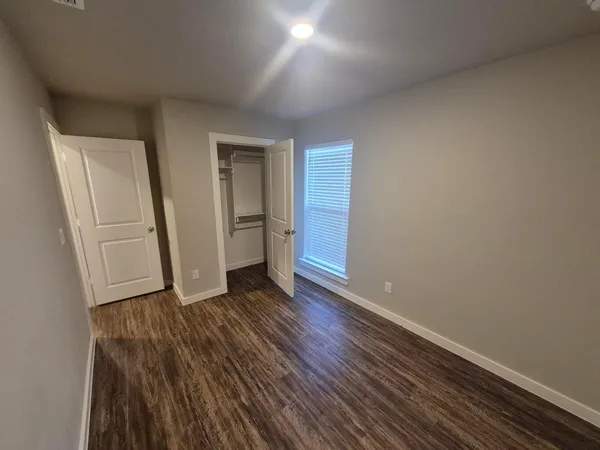 an empty room with wooden floor and closet