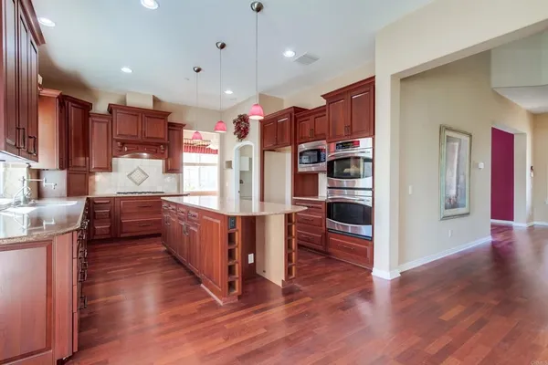 a large kitchen with kitchen island granite countertop wooden cabinets a sink and dishwasher