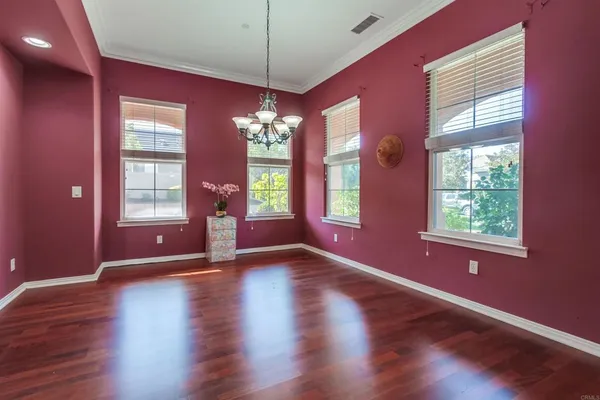 a view of an empty room with window and wooden floor