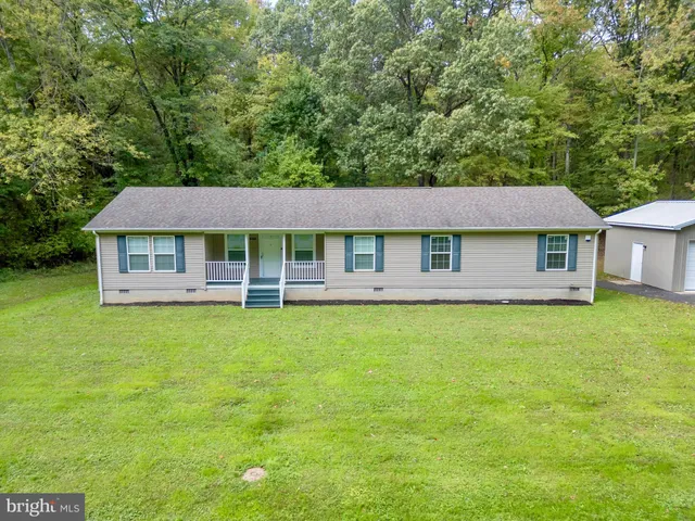 a view of a house with a yard and large trees