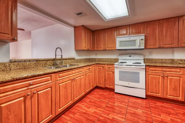 a kitchen with granite countertop wooden cabinets stainless steel appliances and a sink