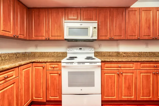 a kitchen with granite countertop wood cabinets stainless steel appliances and a sink