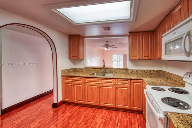 a kitchen with granite countertop wood cabinets and a stove