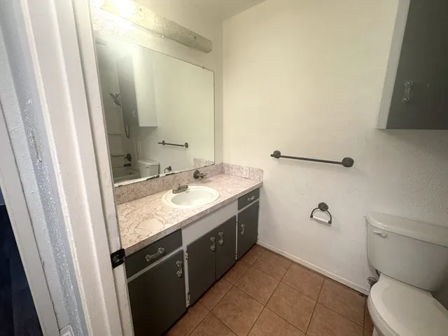 a bathroom with a granite countertop sink toilet and mirror