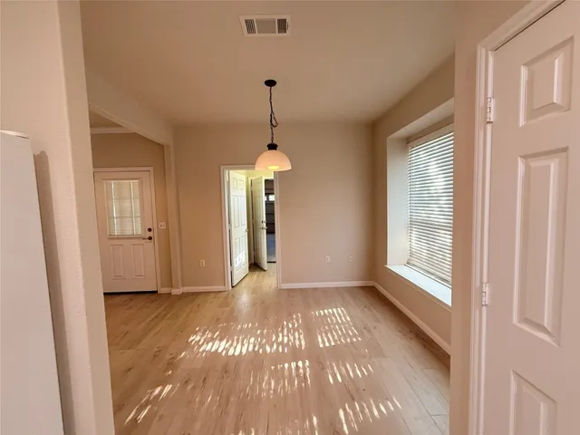 a view of a room with wooden floor chandeliers and kitchen view