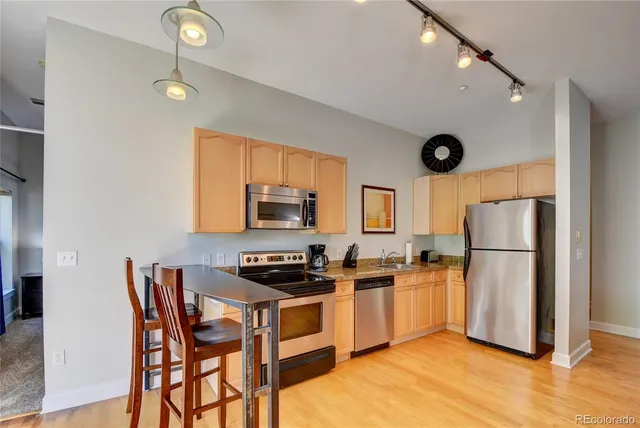 a kitchen with stainless steel appliances a refrigerator a stove a sink a dining table and chairs