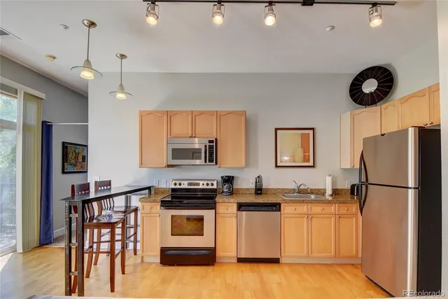 a kitchen with stainless steel appliances granite countertop a refrigerator a stove a sink dishwasher and a refrigerator with wooden floor