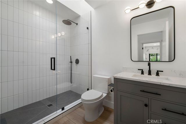 a bathroom with a toilet a sink a glass door a shower and a mirror