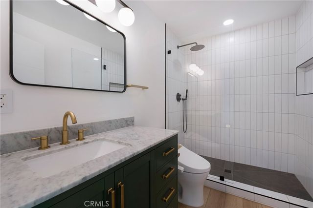 a bathroom with a granite countertop sink a toilet and shower
