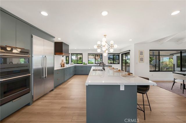 a large kitchen with granite countertop a large counter top stainless steel appliances and cabinets