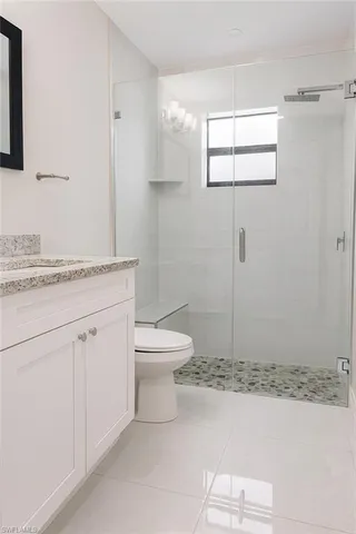 a bathroom with a granite countertop sink mirror vanity and toilet