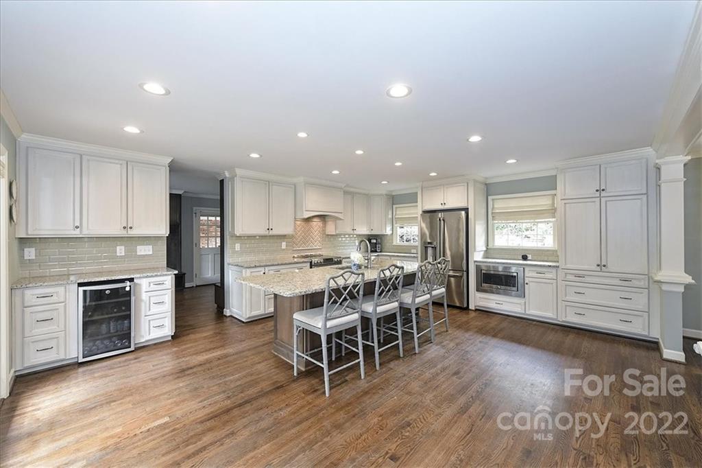3100 Mountainbrook Road Charlotte, NC 28210 - Photo 21 of 48 a kitchen with stainless steel appliances kitchen island granite countertop a stove top oven a sink dishwasher a dining table and chairs with wooden floor