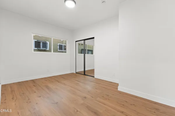 a view of an empty room with wooden floor and a window