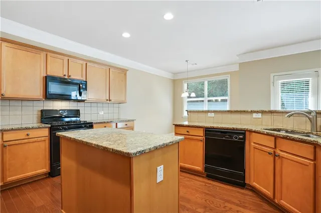 a kitchen with stainless steel appliances granite countertop a sink stove microwave and refrigerator