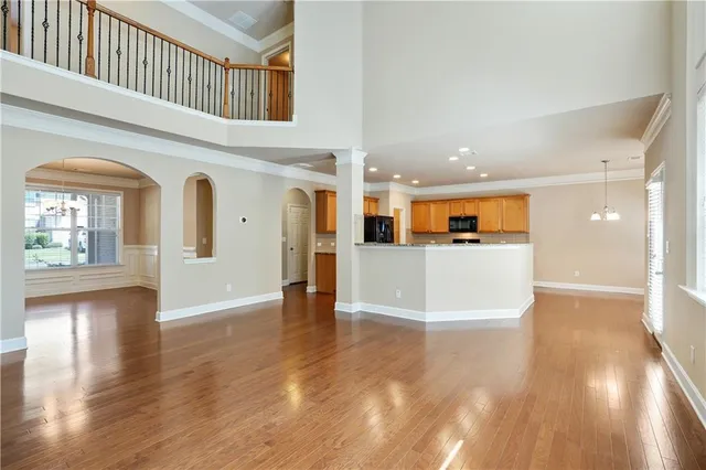 a view of a living room with wooden floors and kitchen view