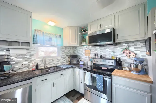 a kitchen with granite countertop white cabinets and white appliances