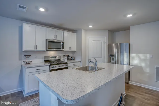 a kitchen with stainless steel appliances granite countertop a stove a sink a microwave a dining table and chairs with wooden floor