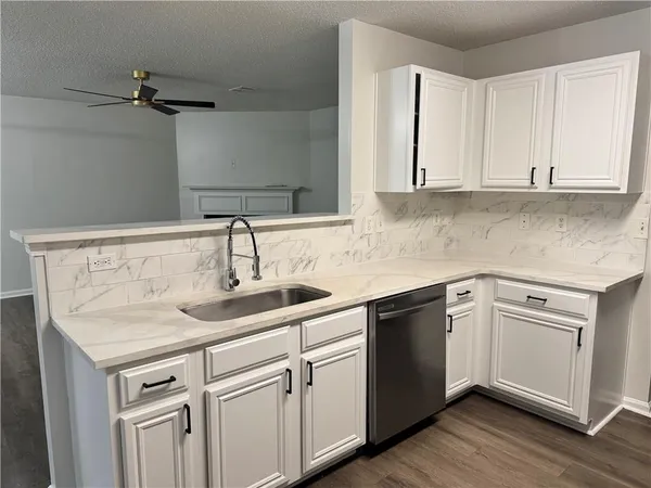 a kitchen with white cabinets sink and dishwasher