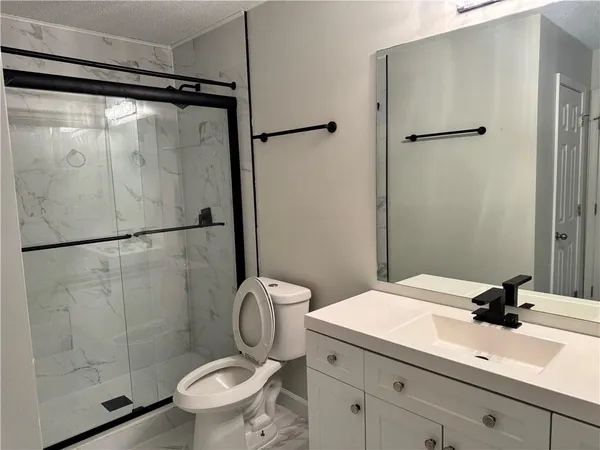 a bathroom with a granite countertop sink toilet and shower