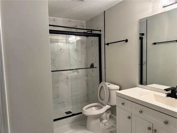 a bathroom with a granite countertop sink toilet and shower
