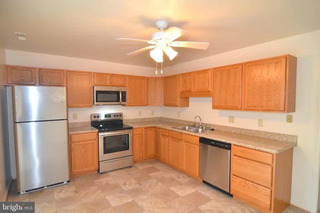 a kitchen with stainless steel appliances granite countertop a stove a sink dishwasher a refrigerator with a dining table and chairs