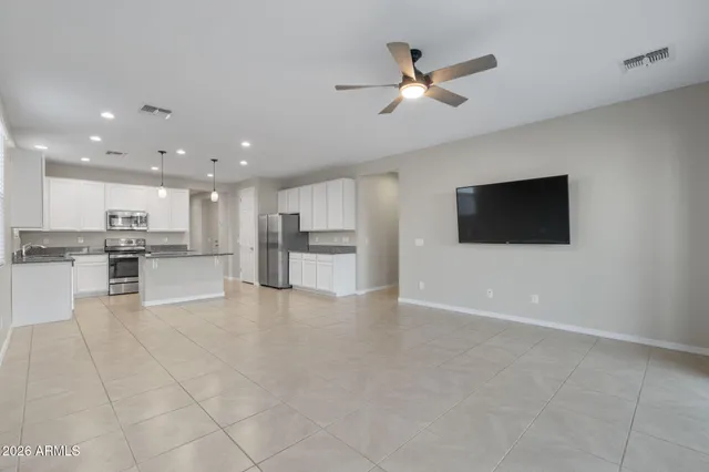 a view of kitchen with stainless steel appliances kitchen island refrigerator stove and white cabinet