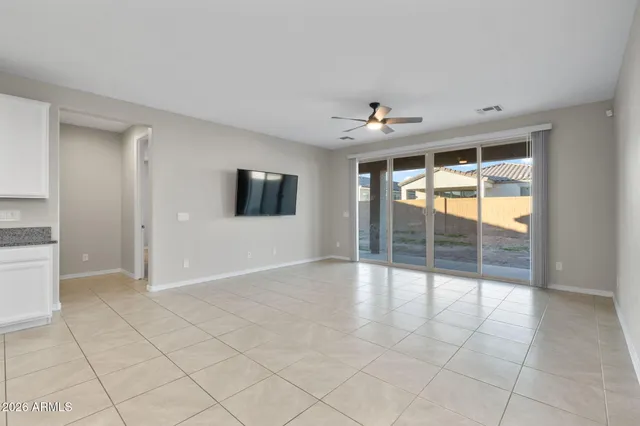 an empty room with floor to ceiling windows and chandelier fan