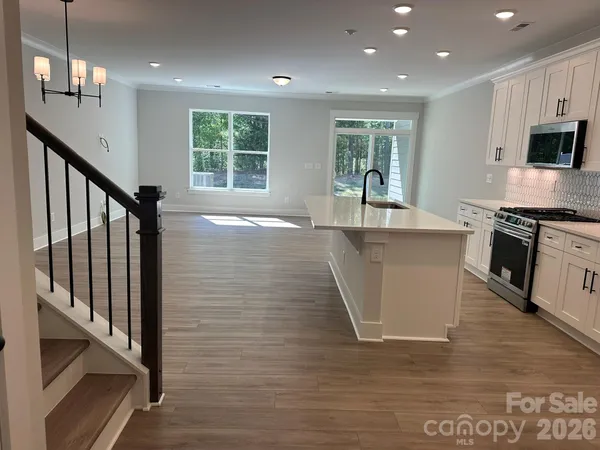 a kitchen with stainless steel appliances granite countertop a sink a stove and a wooden floors