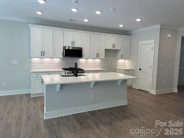 a kitchen with kitchen island granite countertop a stove and a wooden floors