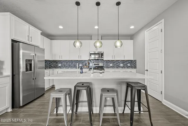 a kitchen with kitchen island granite countertop a sink a center island stainless steel appliances and cabinets
